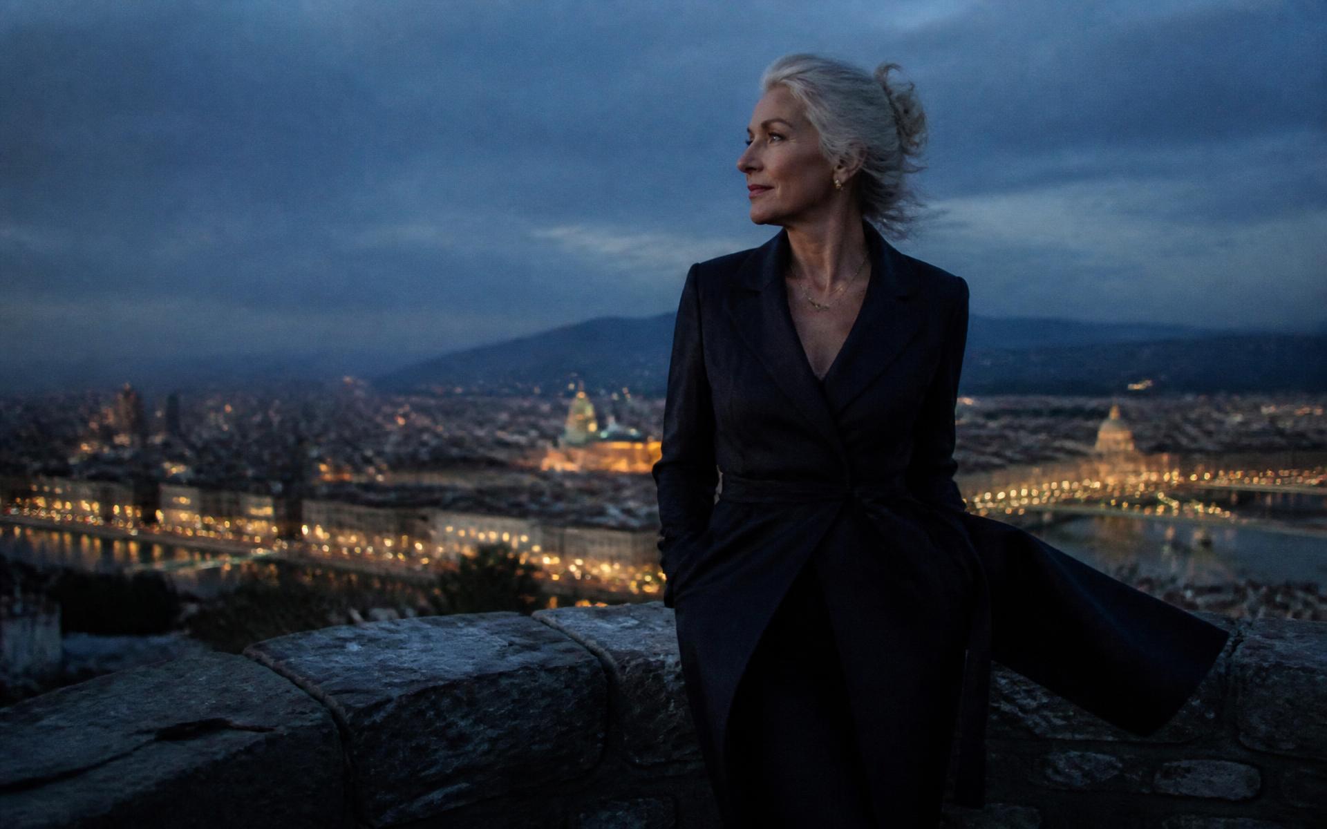 A woman looking out over a city at dusk